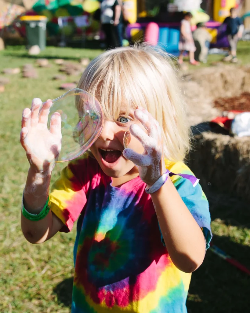 Boy enjoying bubble play as part of the children’s event entertainment at a family festival.