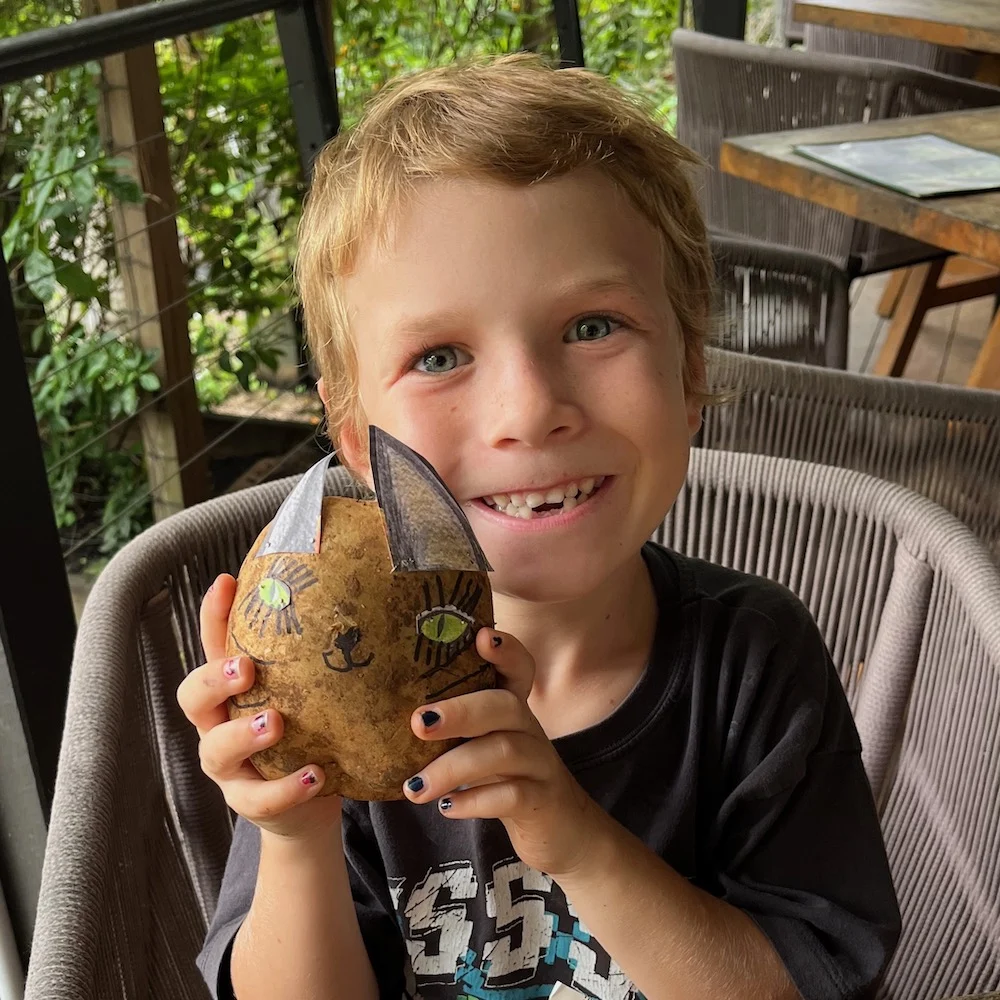 Boy showing off his art creation at a school holiday workshop