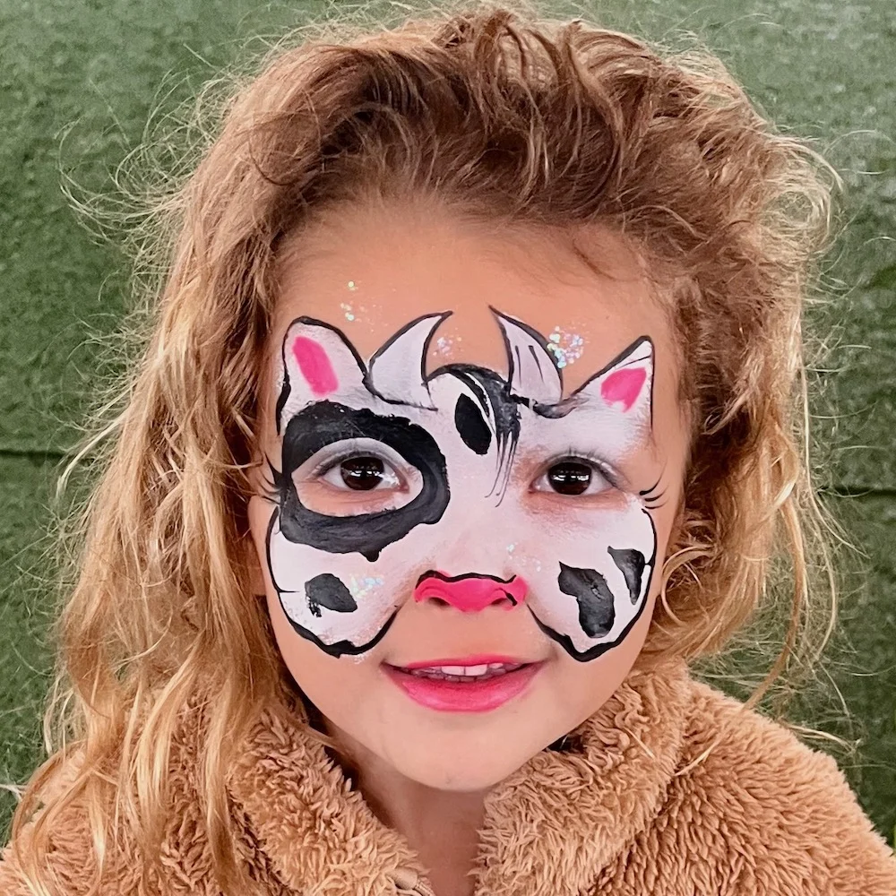 Child at a KidzKlub face painting station with colourful kids design at an event at Byron Bay.