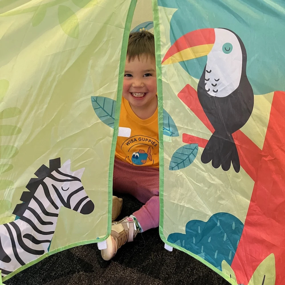 Boy playing in a book nook at a KidzKlub supervised children’s area with safe event childcare and babysitting.