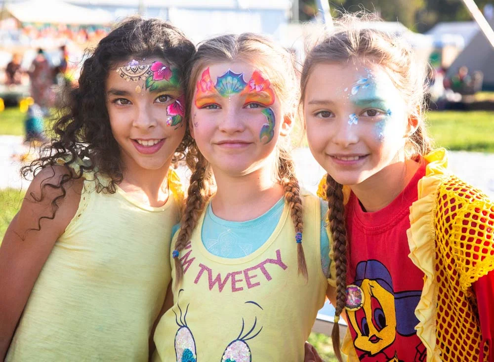 3 girls who have just had their faces painted by professional facepainter